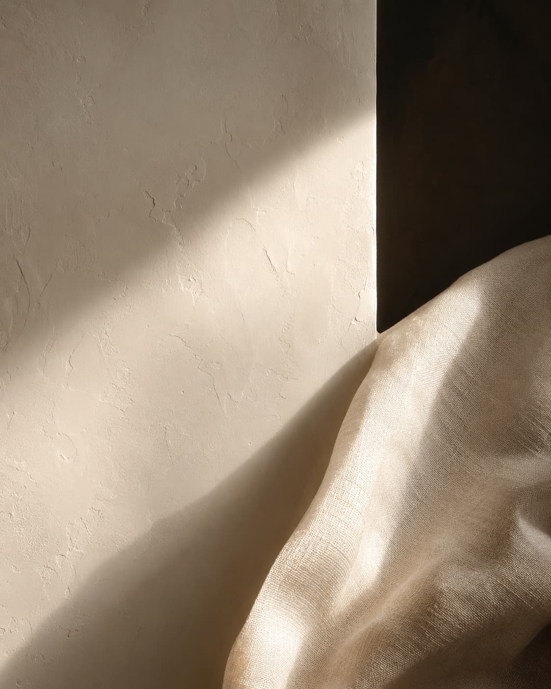 Ivory plaster and folded raw silk with deep, warm shadows in gentle light