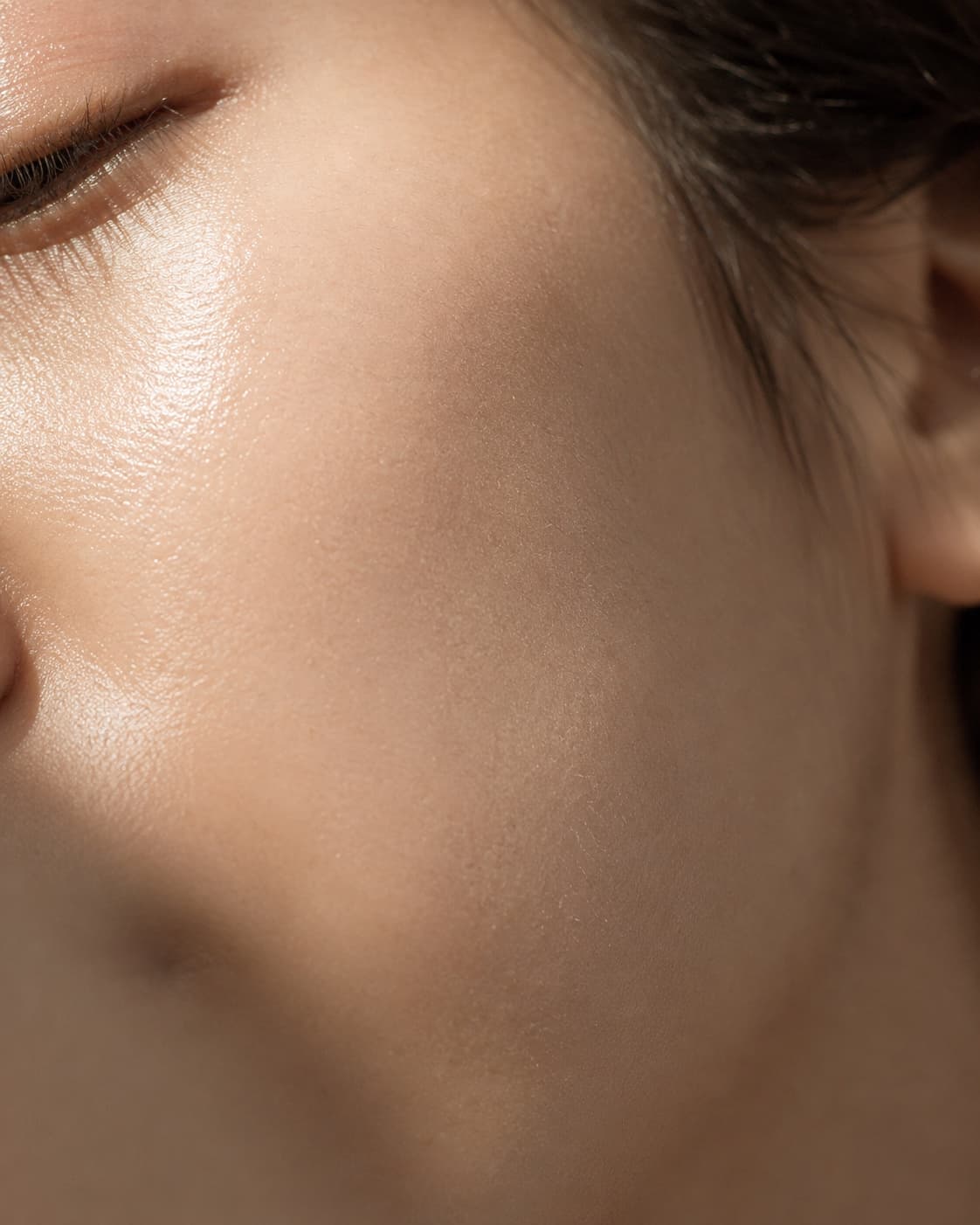 Smooth, healthy-looking facial skin with a hydrated glow in soft, warm light